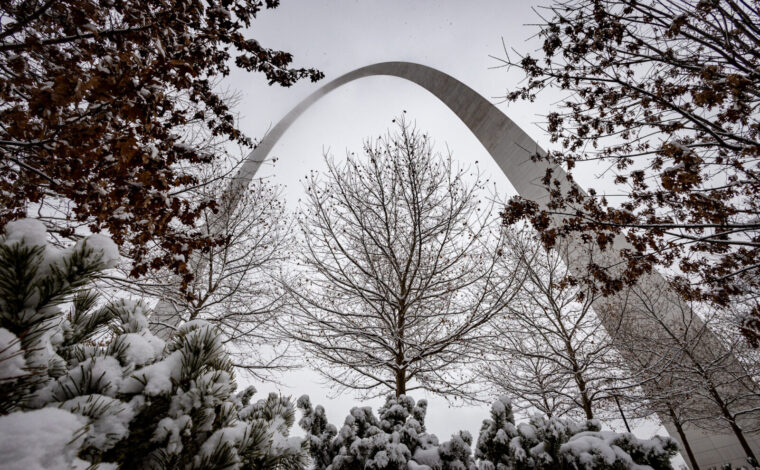 Snow covered trees and shrubs frame the Gateway Arch.