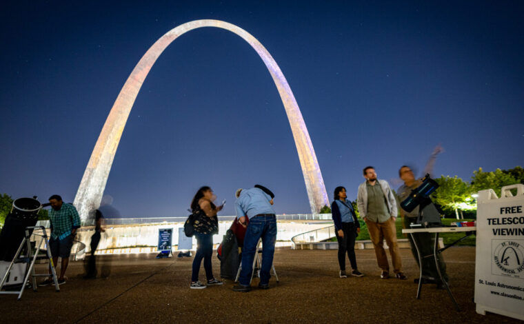Gateway Arch National Park visitors look through a telescope at night during a Gateway to the Stars event